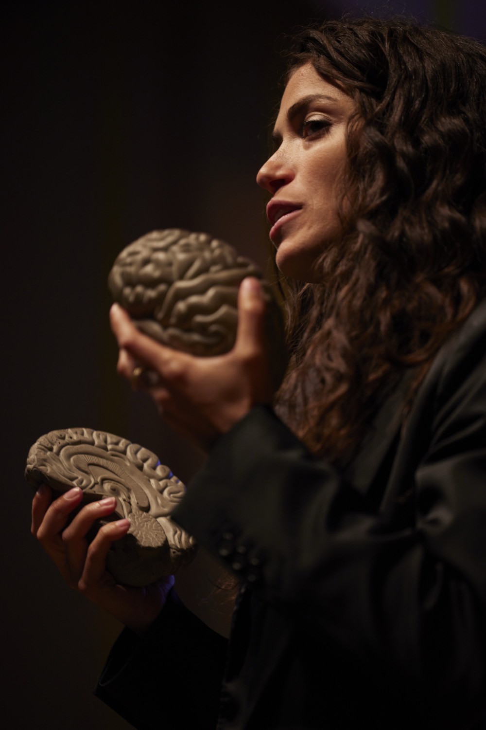 Fran Dal Corso on stage holding anatomical brain models
